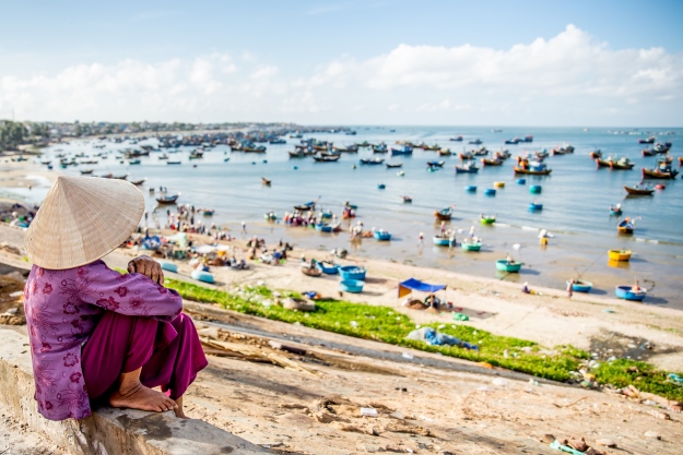 lady in non la looking over mui ne beach, Vietnam