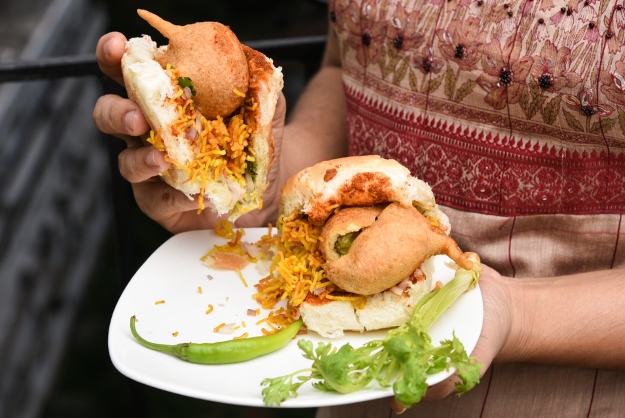 Woman eating vegetarian Vada Pav in India