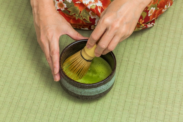 Woman in a kimono whisking matcha tea