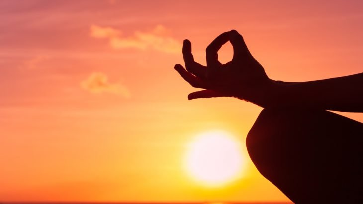 Women meditating at sunset