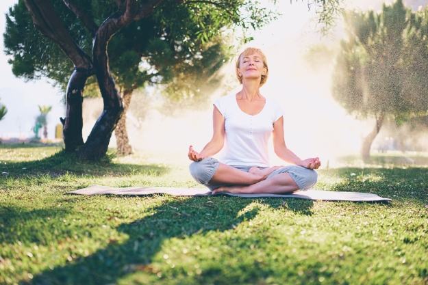 Woman meditating on grass in the sunshine