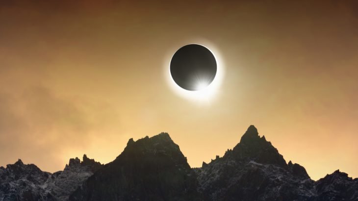 Solar eclipse over jagged mountains