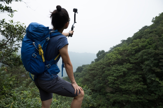 Woman with action cam taking photos of a forest