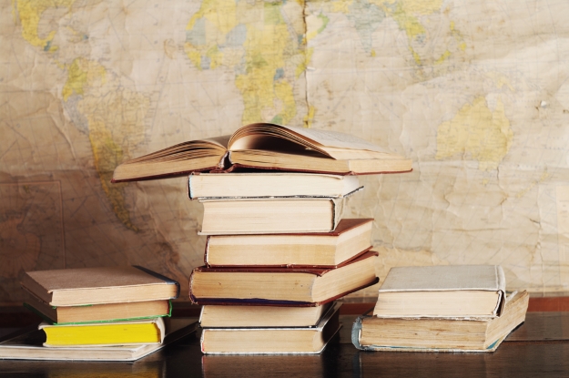 A pile of books in front of a large map