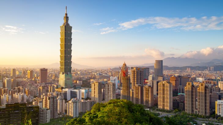 Aerial view of Taipei skyline at sunset featuring the iconic Taipei 101 and surrounding modern buildings.