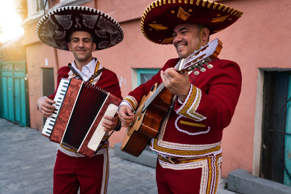 Two mariachi musicians perform with guitar and accordion, wearing traditional charro attire and sombreros, celebrating Mexico’s vibrant culture.