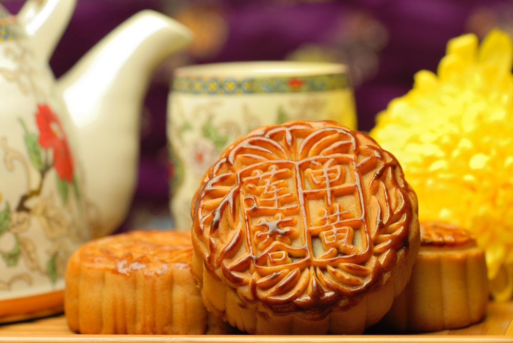 Moon cakes, a popular Moon Festival snack, sat on a plate in front of a tea service, ready to be eaten.