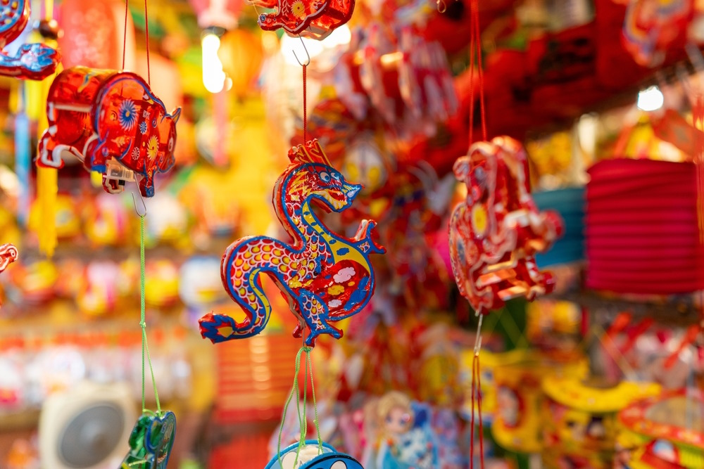 Popular Moon Festival decorations, including red dragons, pigs and rabbits, hanging on a colourful market stall.